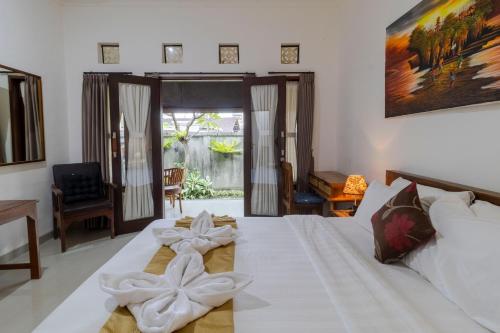 a bedroom with a bed with white sheets and bows at Taman Bali Homestay Sanur in Sanur