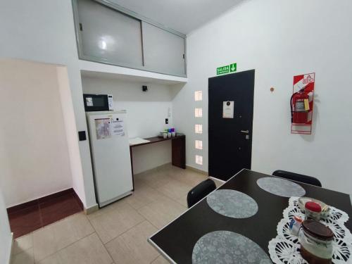 Zimmer mit einem Tisch und einer Küche mit einem Kühlschrank. in der Unterkunft Aisha Alojamiento in Salta