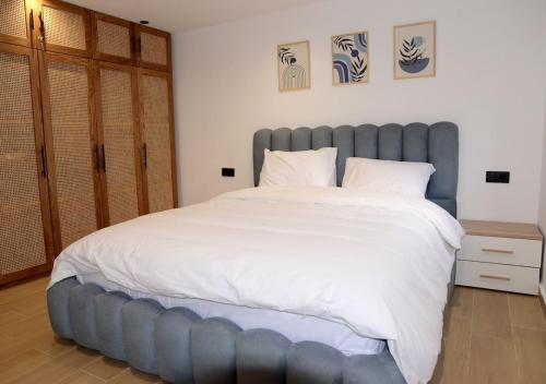 una camera da letto con un letto grande con testiera blu di duplex bord de mer résidence restinga smir a Restinga Smir