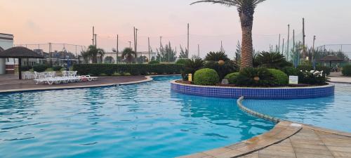una piscina in un resort con una palma di Casa térrea no condomínio Atlântico Villas Club! a Osório