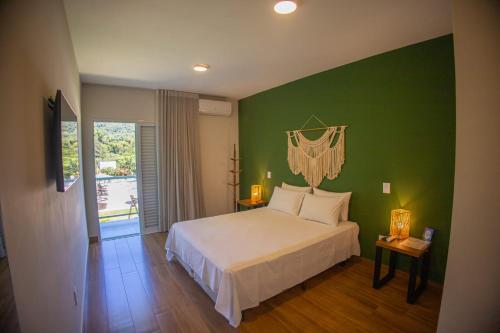 a bedroom with a bed and a green wall at Pousada Thermas das Montanhas in Águas de Lindóia