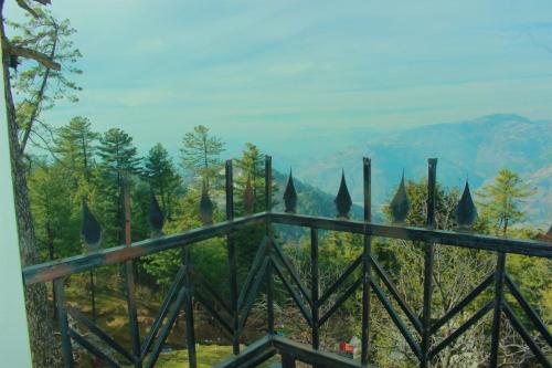 a fence with trees and mountains in the background at Mount heaven Hotel in Murree