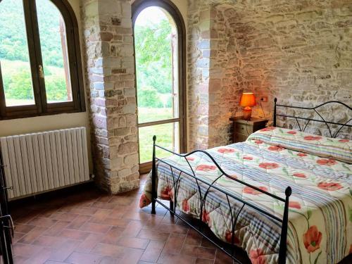 ein Schlafzimmer mit einem Bett in einem Zimmer mit Fenstern in der Unterkunft Villa Sole Vini in the Heavenly Heart of Umbria on Top of the World sleeps 50 in Bazzano di Spoleto