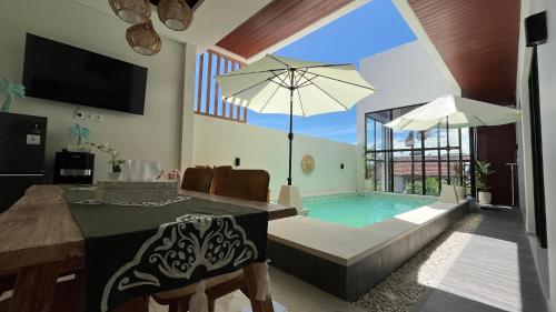 Una sala de estar con una piscina, una mesa y una sombrilla. en Puspa Nirwana Villa, en Kerobokan