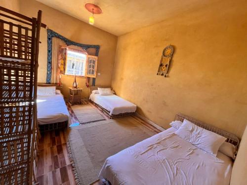 a bedroom with two beds and a window at Zort Siwa - زورت سيوه in Qasr Al Farafirah