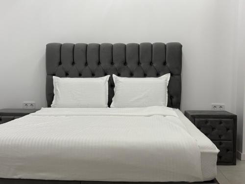 a large white bed with a black headboard and white pillows at Студио in Burgas City