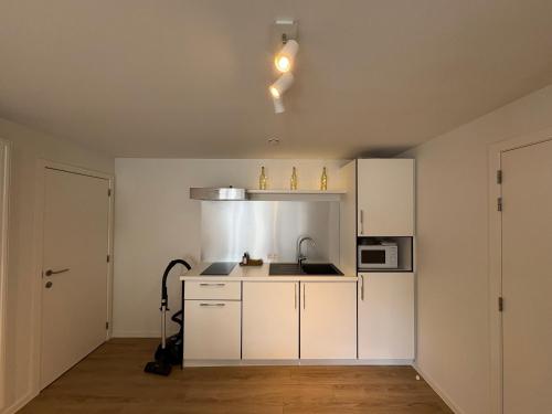 an empty kitchen with white cabinets and a microwave at Briefstreet - Louvain in Leuven