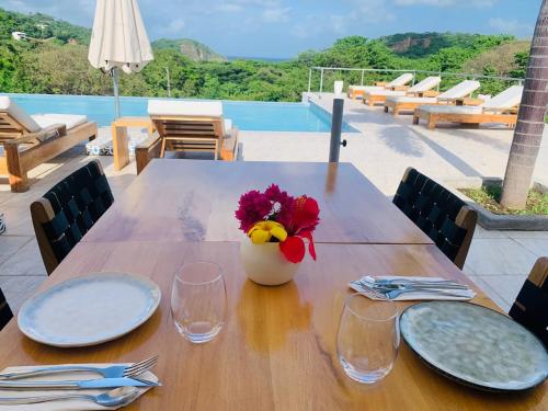 une table en bois avec des assiettes et des verres et un vase avec des fleurs dans l'établissement Villa Francia, à San Juan del Sur