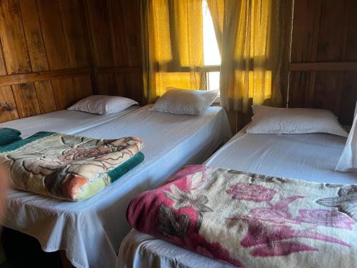 Dos camas una al lado de la otra en una habitación. en Paldor Peak Guest House, en Thāngjet