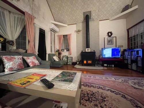 un salon avec un canapé et une télévision dans l'établissement ペンションあけまの森, à Daisen