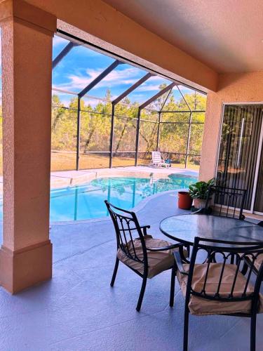 a patio with a table and chairs and a swimming pool at Quiet Naples retreat suite with pool - 1 or 2 bedrooms in Naples