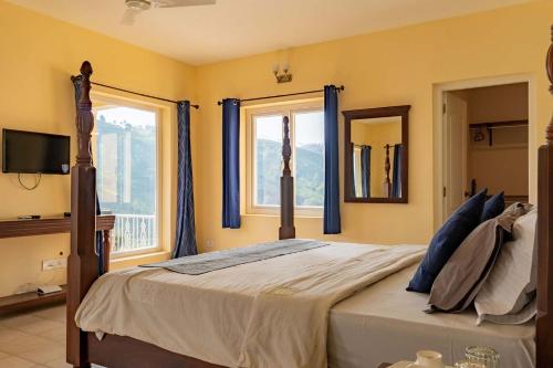 a bedroom with a bed with blue curtains and two windows at Yellow Tulip Luxury Villa by LexStays - Coonoor in Kolakambe