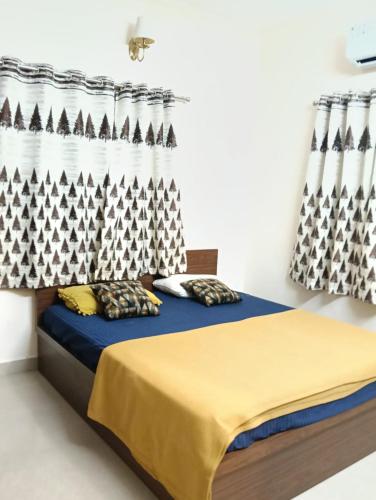 Un dormitorio con una cama con una manta azul y cortinas. en Vg paradise, en Covelong