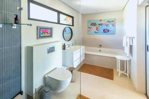 a bathroom with a toilet and a sink and a tub at StonenSea in Plettenberg Bay