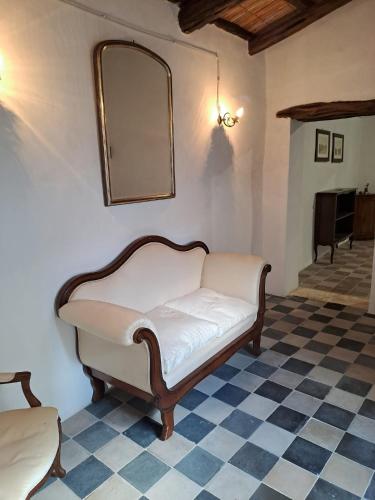un canapé dans une pièce avec un miroir et un sol à damier dans l'établissement Foresteria di Villa Carboni, à Cagliari