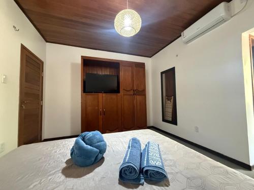 ein Schlafzimmer mit einem Bett, blauen Hausschuhen und einem Fernseher in der Unterkunft Casa Atina - Atins in Atins