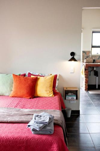 a bedroom with a red bed with colorful pillows at Pecan and Lime Inn The Third Den in Pretoria