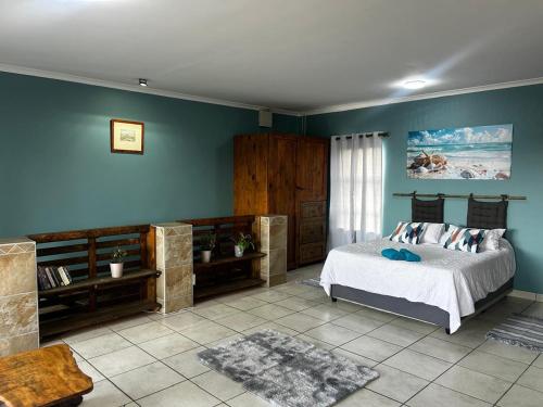 Schlafzimmer mit blauen Wänden und einem Bett in einem Zimmer in der Unterkunft Ocean Nook in Gqeberha