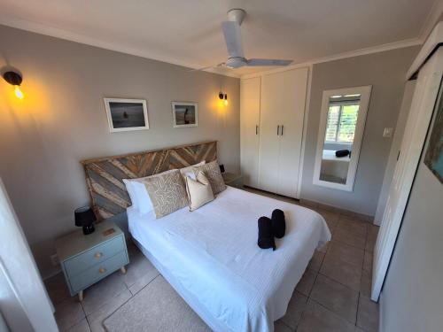 a bedroom with a bed with a pair of shoes on it at Unit 40 Chakas Rock Chalets in Ballito