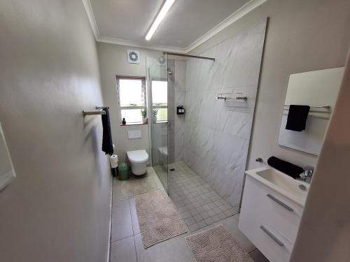 a bathroom with a shower and a toilet and a sink at Unit 40 Chakas Rock Chalets in Ballito