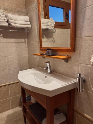 a bathroom with a sink and a mirror and towels at Elena Hotel in Kozani