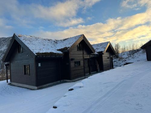 a wooden house with snow on the roof at Myrkdalen Lodge II, luxury family cabin in Helgatun