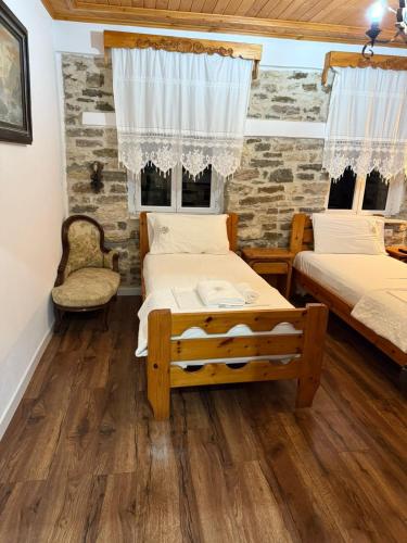 Dos camas en una habitación con suelo de madera. en Hotel Drasa, en Gjirokastra