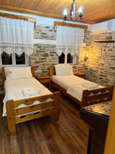 Un dormitorio con dos camas y una pared de piedra. en Hotel Drasa, en Gjirokastra