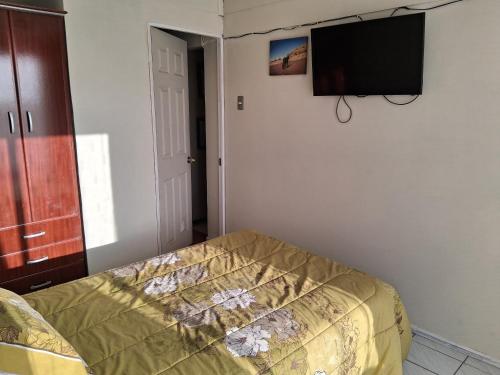 une chambre avec un lit et une télévision à écran plat au mur dans l'établissement Homestay Iquique, à Iquique