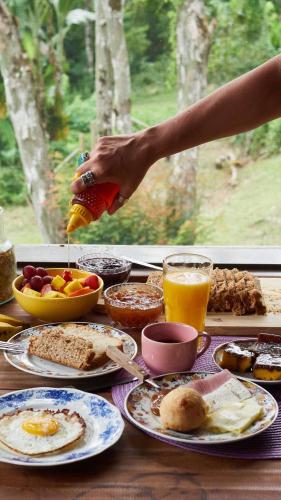een tafel vol eten met een persoon die een drankje inschenkt bij Pousada Rancho da Serra PETAR in Iporanga
