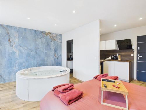 a bathroom with a tub and a bed with pink towels at La petite suite Ponote in Le Puy en Velay