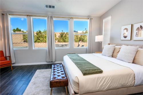 a bedroom with a large bed and large windows at #Marbella Lane - Desert Dream Pool Spa & Games in Desert Hot Springs