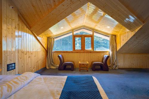 a bedroom with a bed and two chairs and a window at Hide-In Kasol in Kasol