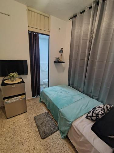 a bedroom with a bed and a television and a window at La Guarida de Mela in Santo Domingo