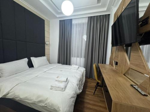 une chambre avec un lit et un bureau avec une télévision dans l'établissement Hotel Comfort, à Tirana