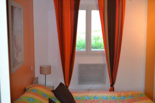 une chambre avec un lit et une fenêtre avec des rideaux dans l'établissement Rez-de-villa Taglio-Isolaccio, à Taglio-Isolaccio