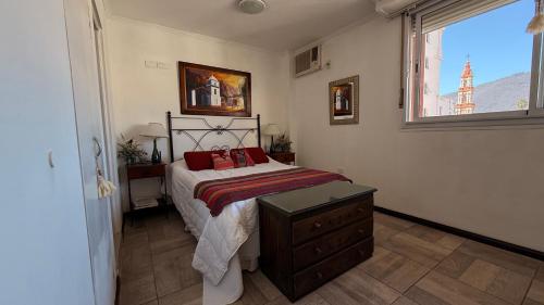 ein Schlafzimmer mit einem Bett mit roten Kissen und einem Fenster in der Unterkunft En el Corazón de Salta in Salta