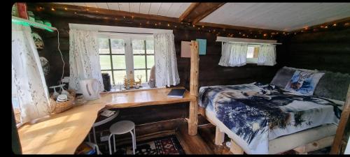 Un dormitorio con una cama, un escritorio y una ventana. en Cozy little log cabin, dog allowed, sauna, en Åseral