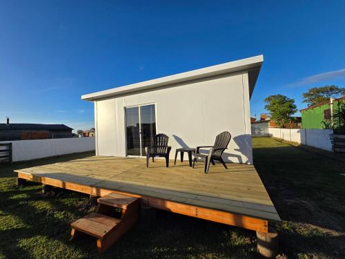 eine Holzterrasse mit 2 Stühlen und einem Tisch darauf in der Unterkunft Maridalba 2 in La Coronilla