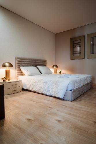Un dormitorio con una gran cama blanca y dos lámparas. en Rua Fraga - Os Maias, en Vila do Conde