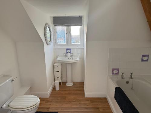une salle de bain avec toilettes, lavabo et baignoire dans l'établissement Cottage on remote wild coast, à Bawdsey