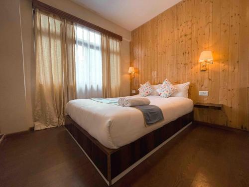 ein Schlafzimmer mit einem großen Bett mit Fenster in der Unterkunft Daphne House in Darjeeling