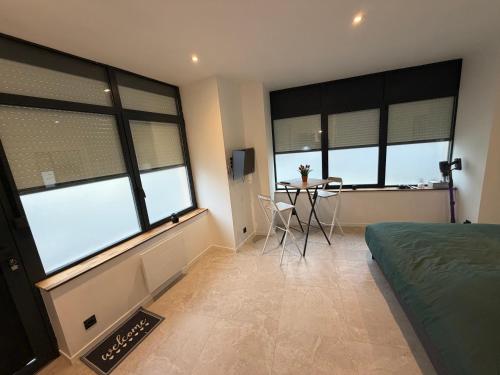 1 dormitorio con ventanas, mesa y cama en Brest Centre Studio, en Brest