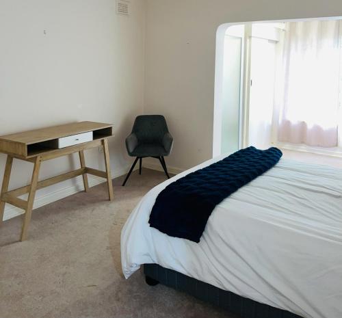 a bedroom with a bed and a desk and a chair at LaPoch Guesthouse in Durban