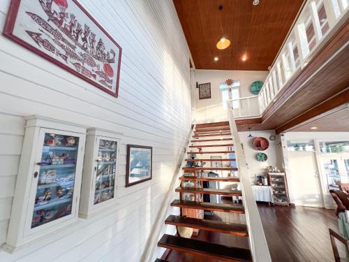 eine Wendeltreppe in einem Haus mit Büchern an der Wand in der Unterkunft Baan Talay Koh Chang in Ban Map Khangkhao