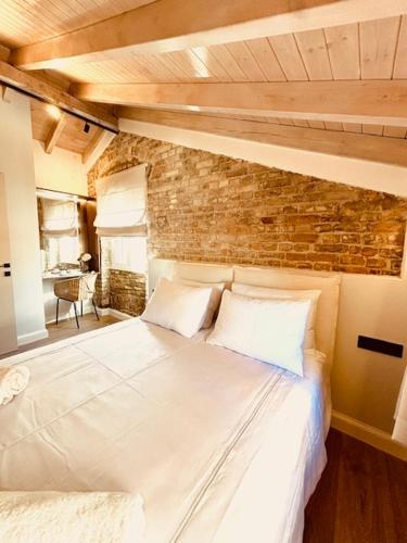 a large white bed in a room with a brick wall at L'Atelier TOP LOCATION in Corfu