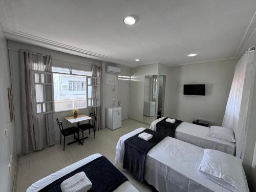 a bedroom with two beds and a table with a desk at Hospedar Imperial in Campina Grande