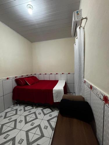 een kleine kamer met een bed met een rode sprei en een kamer met bij Casa da Missi in Cayru