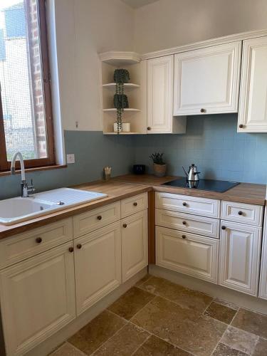 a kitchen with white cabinets and a sink and a window at Comfort with garden in Fécamp