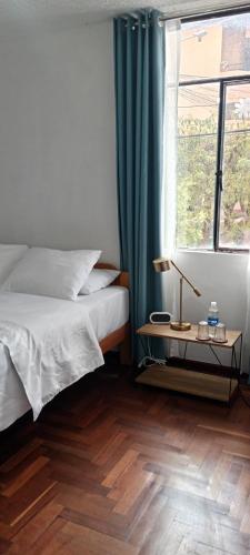 a bedroom with a bed and a window and a wooden floor at Sonqo Andino Departamento in Cusco